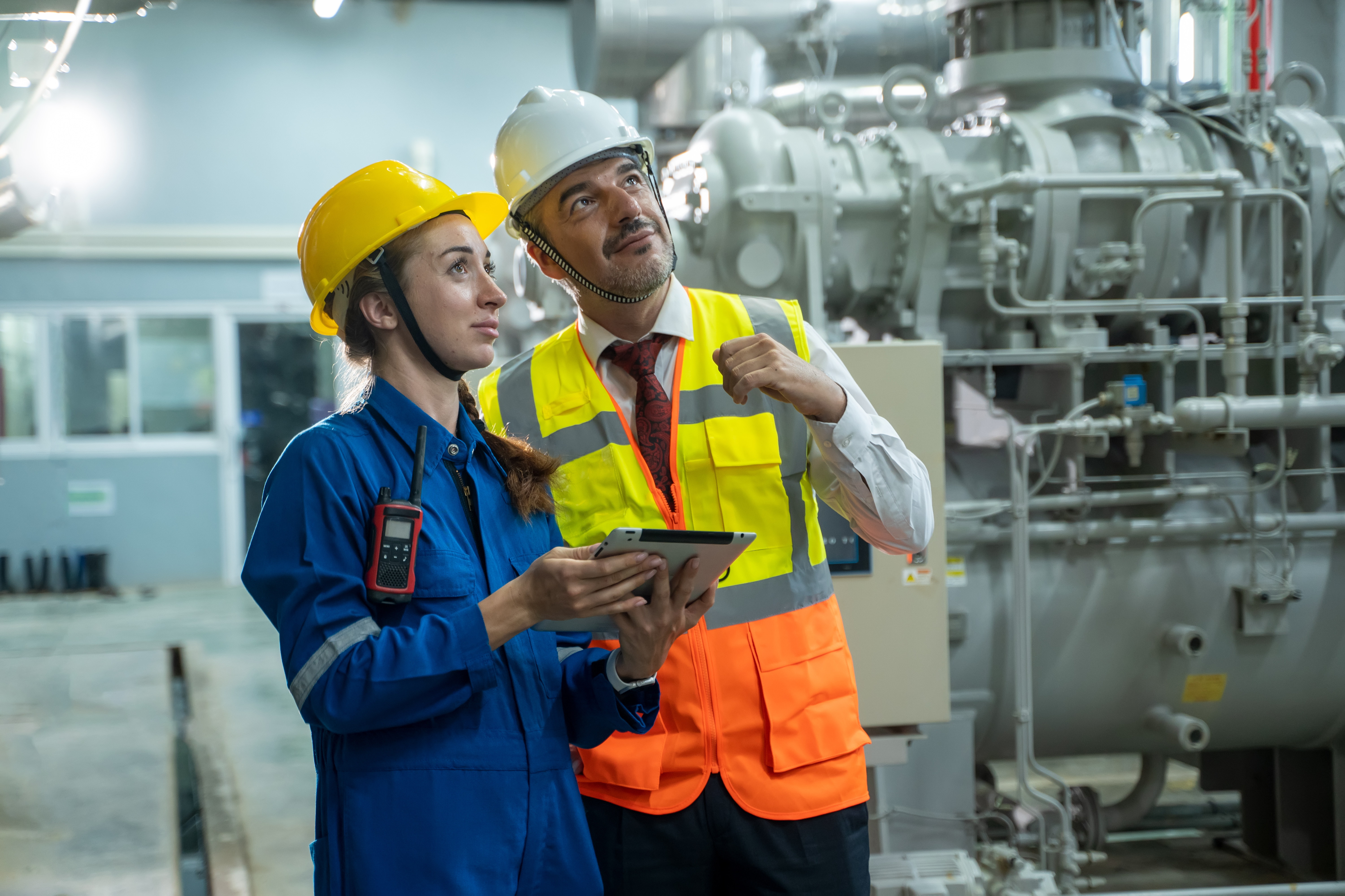 Engineer with technical worker checking and working at large industry factory.